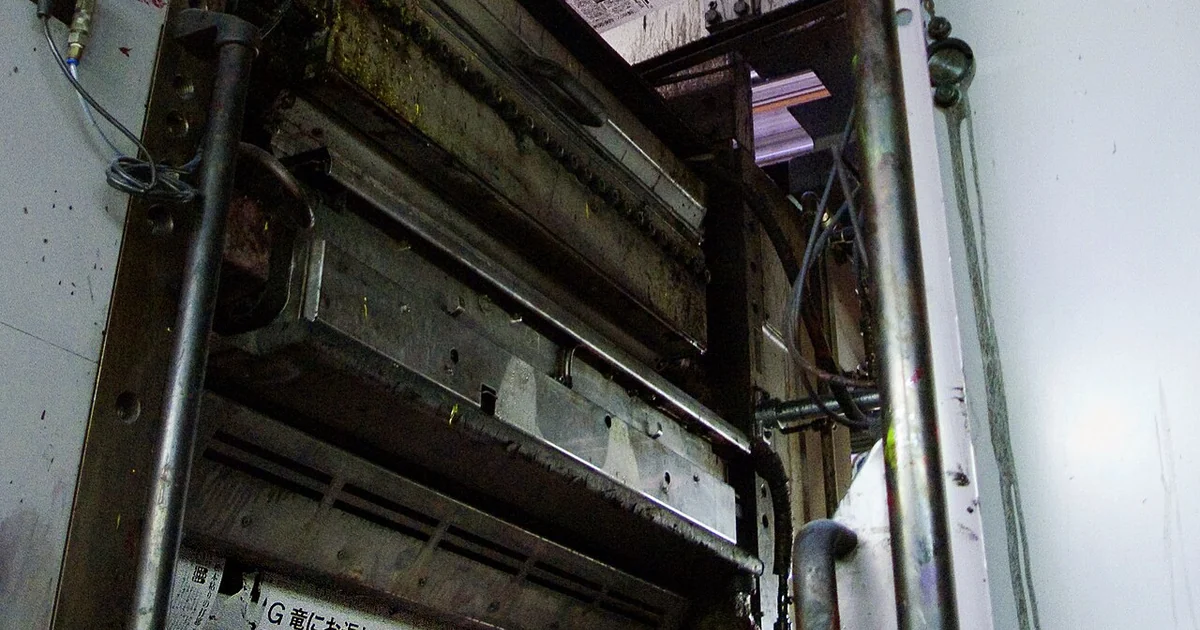 A web-fed, offset printing press in use to print a newspaper. The plate cylinder, visible at bottom with ink, contains the image in positive form and transfers it to an offset cylinder that then deposits the ink on the page.